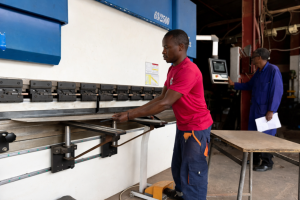 KCrea Manufacturing worker applying powder coat finish in Kigali workshop